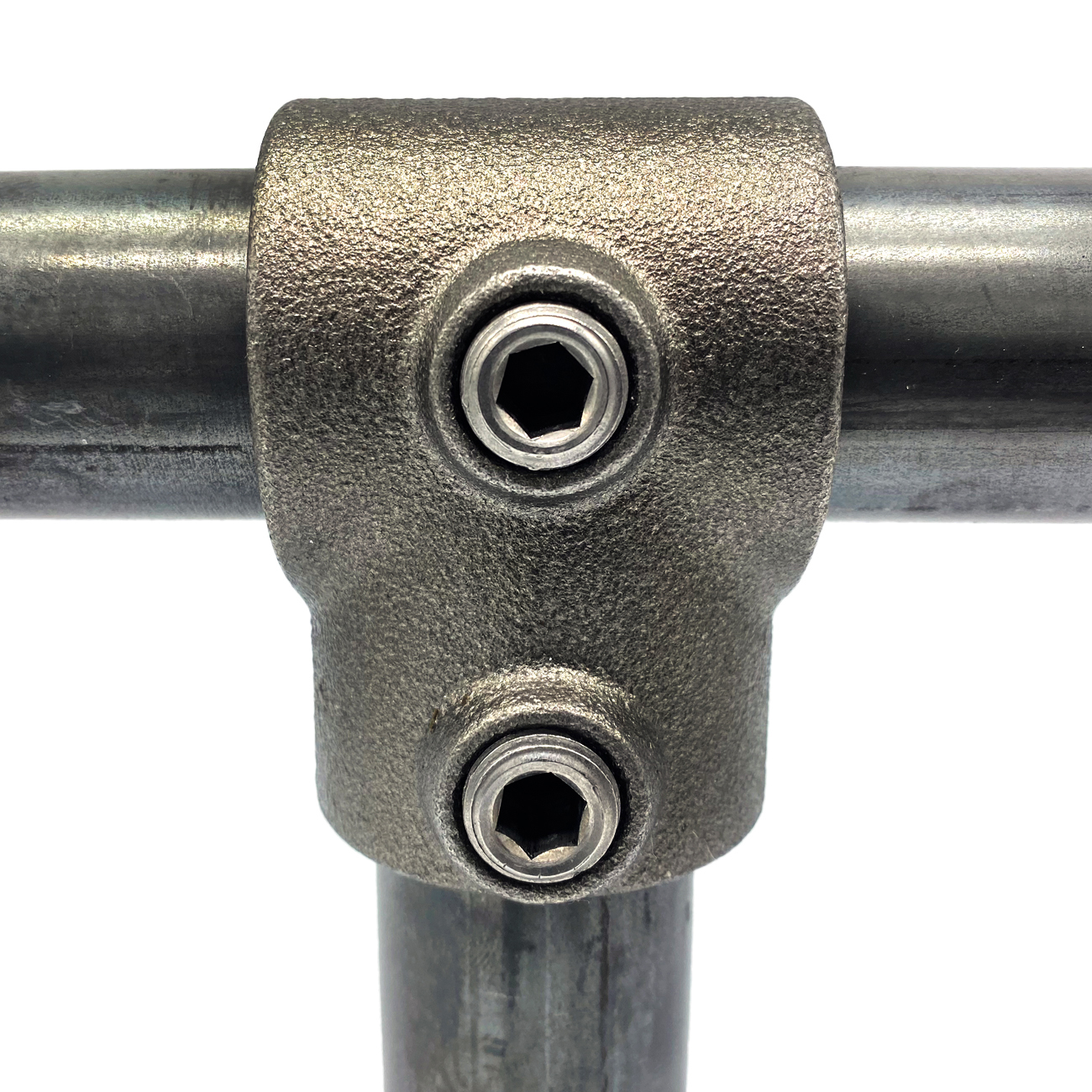 Gros plan sur un raccord en T métallique robuste, gris foncé, reliant trois tubes nus : deux horizontaux, un vertical. Deux vis à six pans creux fixent les tubes de 42,4 mm dans le raccord « Lunado 101-C ». Fond blanc.