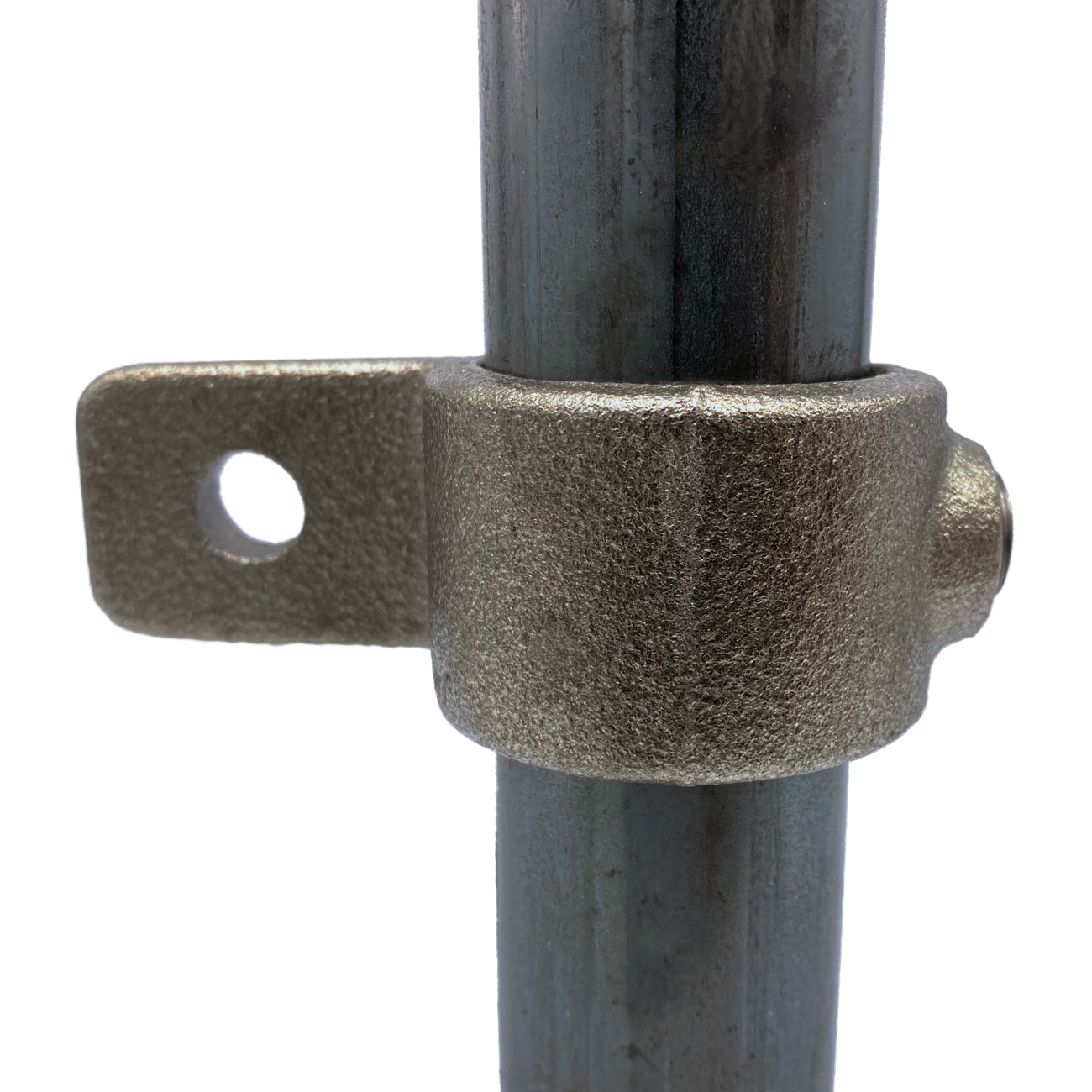A grey, metallic eyelet with a rough surface is clamped tightly around a smooth, vertical metal pipe. On the left, a single tab with a round hole protrudes. Precisely manufactured for securing ropes or rods.