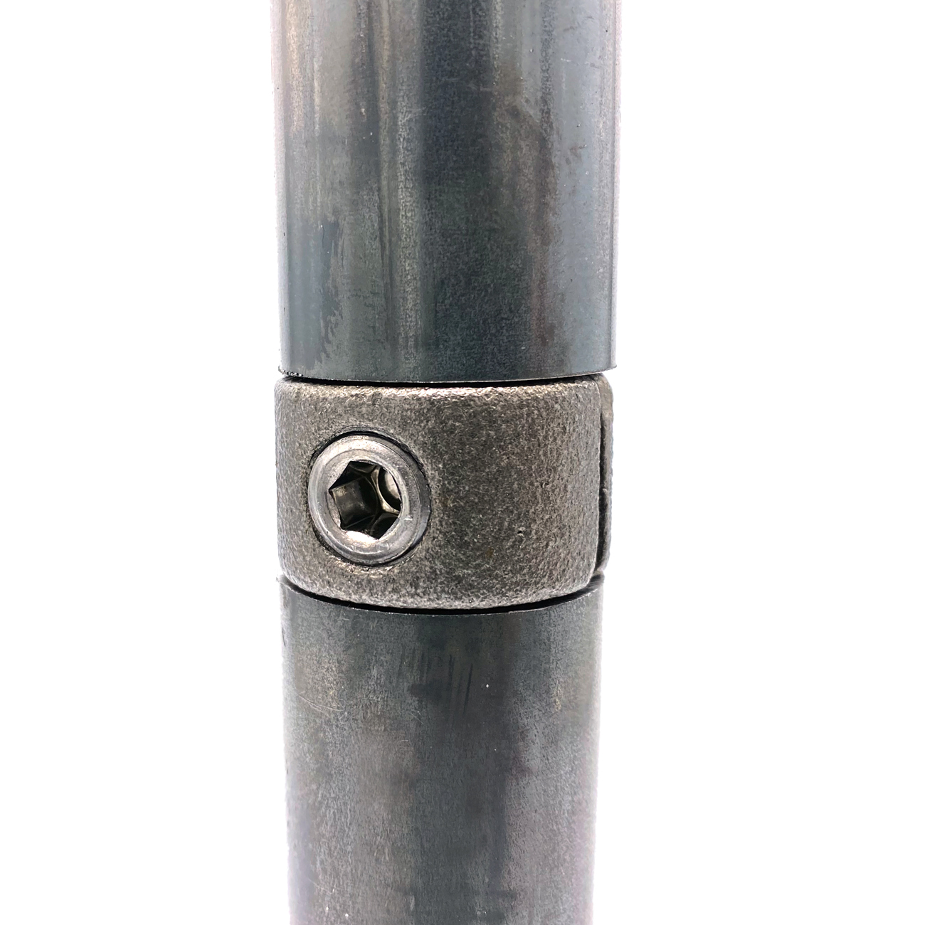 Two matt, dark grey metal tubes are connected at the centre by a robust, textured extension piece. A visible hexagonal screw head at the front of the connector secures the assembly. The detailed view shows the sturdy tube connection.